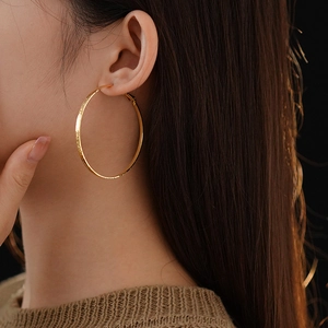 Detailed close-up of textured gold hoop earring showing metallic finish on model