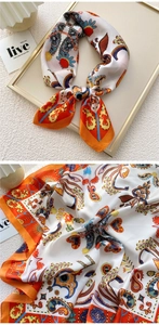 Detailed close-up of patterned square silk scarf with orange and white paisley print