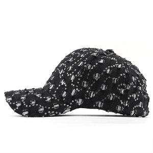 Close-up of distressed denim baseball cap featuring metal rings and star sequins