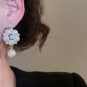 Close-up of elegant gold flower stud earrings with pearls and crystals on a female model