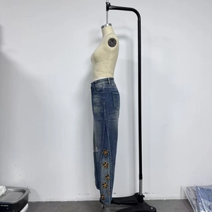 Detail of yellow flower embroidery on high-waist vintage blue denim pants