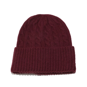 Detail of dark red cable knit beanie showing thick warm wool texture and ribbed cuff