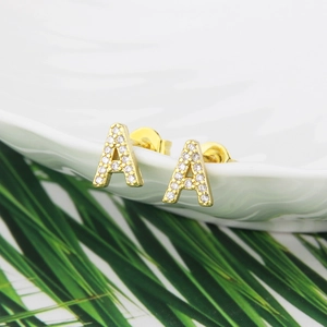Macro detail of gold-plated letter A stud earring with micro-paved white zircon stones