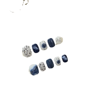 Short handmade press-on nails in blue and black marble design with starry glitter accents