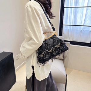 Detail shot of a black beaded shell bag with fringe tassels and gold clasp closure