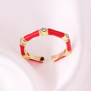 Close-up of a red enamel bamboo ring with gold plating and cubic zirconia on silk