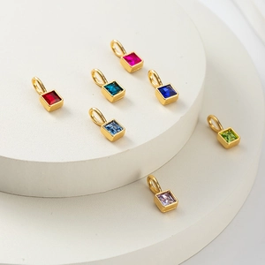 Detail of colorful birthstone charms in gold square settings on white display tiers