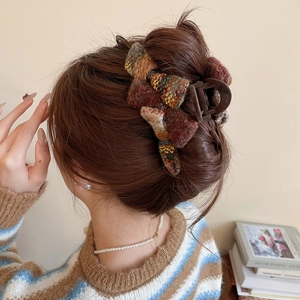Detail view of large tweed bow hair claw clip worn on model for an elegant winter look
