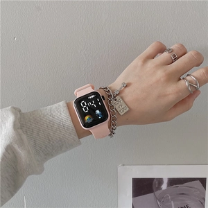 Pink silicone sports watch shown with silver chain bracelet and rings in a modern style