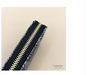 Detailed macro view of the gold metal zipper and geometric floral print on women's long purse