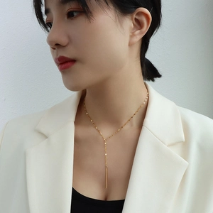 Collier en Y doré de style français minimaliste avec pendentif barre porté par un mannequin