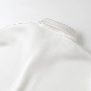 Dettaglio del colletto della camicia in raso bianco con trama di seta e lucentezza perlata