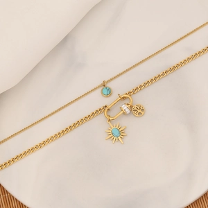 Detail of gold double-layer necklace with turquoise sun and tree of life pendants