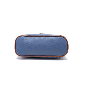 Detailed macro view of the blue lychee-textured leather bag bottom with brown piping edges