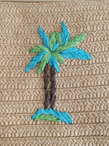 Handwoven straw clutch bag with colorful embroidered palm tree motif for summer