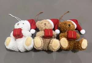 Close-up of three plush Christmas teddy bears in red hats holding small gift boxes