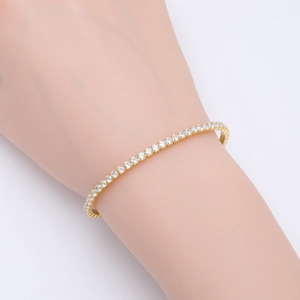 Macro shot of gold-plated tennis bracelet with four-prong set sparkling zircons