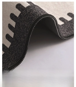 Close-up of durable hemmed edges and dense stitching on a black and white geometric carpet