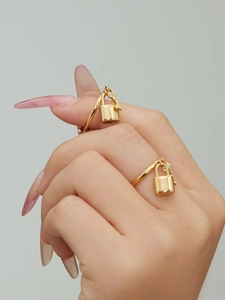 Detail of gold wrap ring featuring a polished lock charm and zircon-studded key pendant