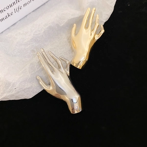 Close-up of gold and silver palm brooches with high-polished metal finish and detail
