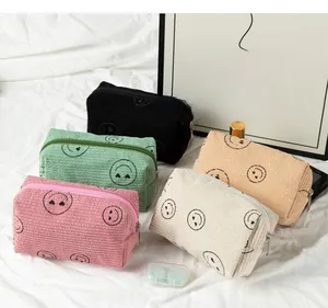 Detail of corduroy makeup bags with smiley heart patterns in five colors on fabric