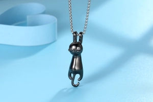 Macro shot of minimalist black cat pendant with sleek long tail on silver chain necklace