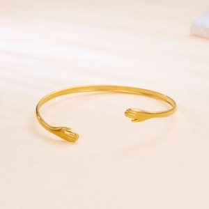 Detailed macro view of the gold hug-shaped open bracelet with a polished metallic finish