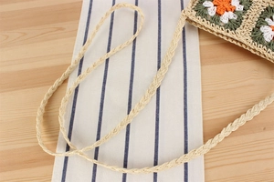 Détail des fleurs au crochet faites à la main sur un sac à bandoulière en paille tissée