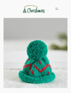 Detail of green knit mini Christmas hat with red wave patterns on a snowy surface