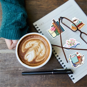 Cozy flat lay of waterproof reading stickers on a notebook beside a cup of latte