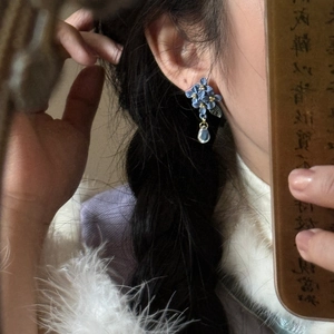 Vintage floral tassel earrings with blue petals and golden accents on a model