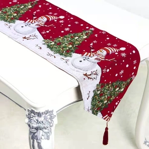 Close-up of Christmas table runner with festive embroidery and red pom-pom tassels