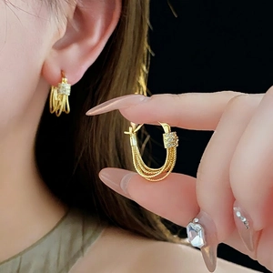 Boucles d'oreilles créoles multicouches plaquées or 14K avec zircons sur un mannequin