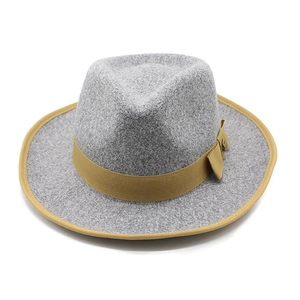 Detail of grey wool fedora hat with contrast tan trim, bow, and metal button accent