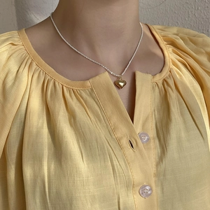 Macro shot of 925 silver heart necklace on neck, minimalist dainty jewelry aesthetic
