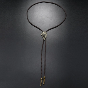 Detailed view of vintage bronze wolf head slider on a braided leather Western bolo tie