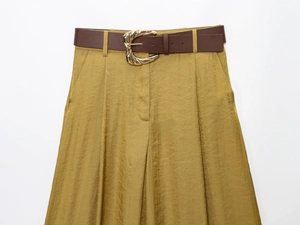 Dettaglio dei pantaloni a gamba larga a vita alta in raso dorato con cintura marrone fibbiata