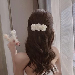 Elegant white camellia hair clip set featuring three fabric roses on wavy long hair