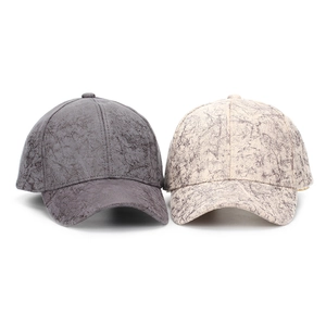 Detail view of two faux suede baseball caps in dark grey and beige with marble crackle texture