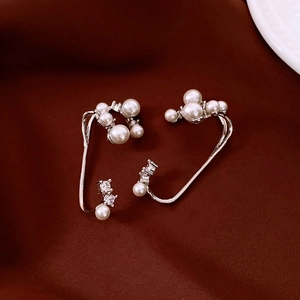 Detail shot of silver ear cuff with white pearls and zircons on red velvet background