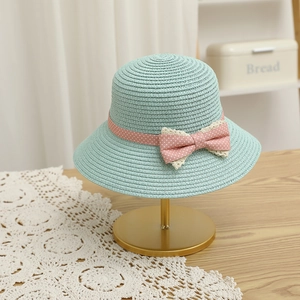 Close-up of mint green straw hat featuring pink polka dot bow and delicate lace trim