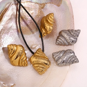 Detailed view of gold and silver seashell pendants on a natural shell with water droplets