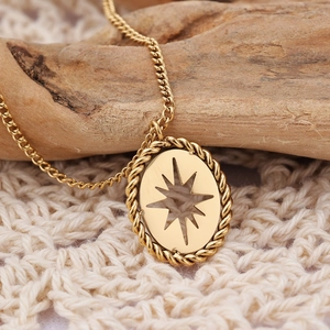 Macro detail of a golden bohemian oval pendant with an eight-pointed star cutout design
