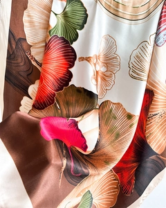 Close-up of silky satin scarf with elegant ginkgo leaf print and vibrant smooth texture
