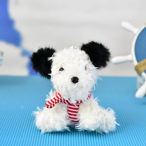 Close-up of a cute fluffy white Westie plush dog keychain with black ears and striped scarf.
