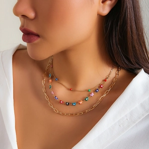 Close-up of layered gold necklace set with colorful butterfly and evil eye charms