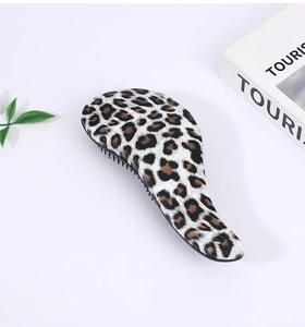 Leopard print hairbrush with air cushion on white desk near green plants and books