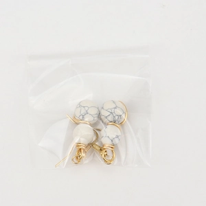 Detail of handmade gold wire wrapped earrings with white marble beads and hook design