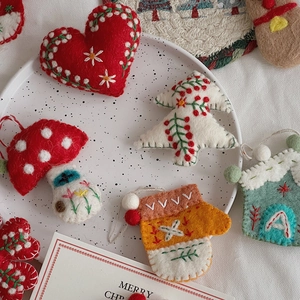 Detail showing various handmade felt Christmas ornaments with intricate floral embroidery