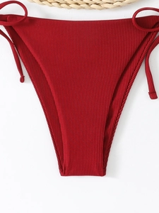 Detail of dark red ribbed bikini bottoms with adjustable side tie strings for resort wear